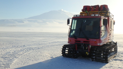 A PistenBully sits on the sea ice with Mt. Erebus in the distance. Turtle Rock, Antarctica. Photo by Timothy R. Dwyer.