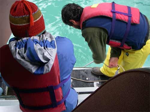 Heidi leans out airplane door to help Darrell pull up a core from the bottom of High Lake.