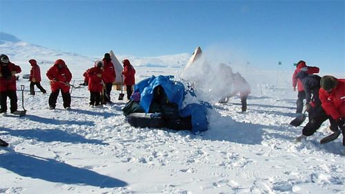 The whole group works together to  build a quinzee.