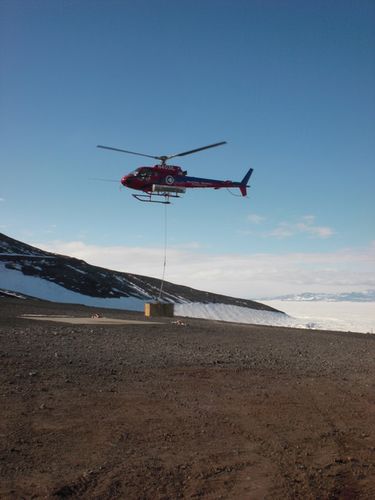 A helicopter taking off with cargo.