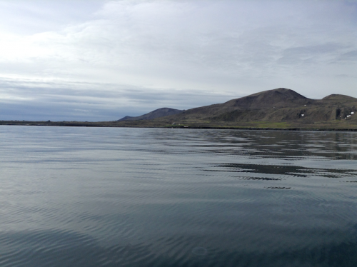 Glassy water and hilly coastline.