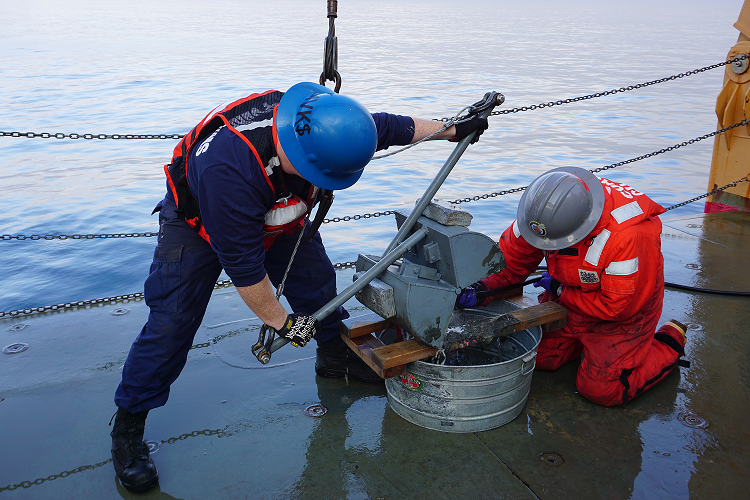 Piper Bartlett-Browne empties the mud out of the van Veen grab on deck. (Photo courtesy of Nicole Villeneuve)