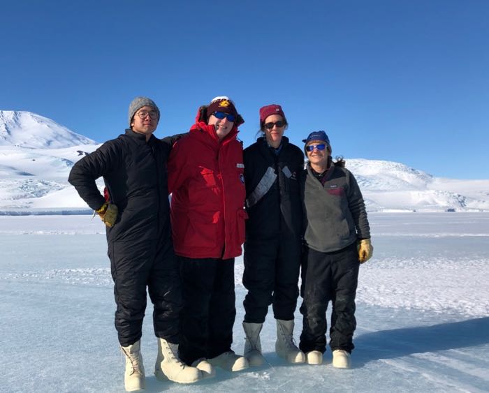 Four people stand on the sea ice in Antarctica