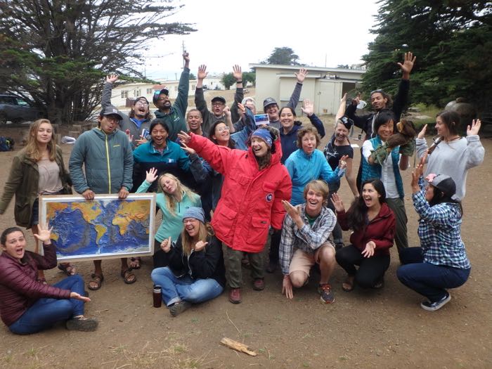 A group of outdoor educators with a map of the world