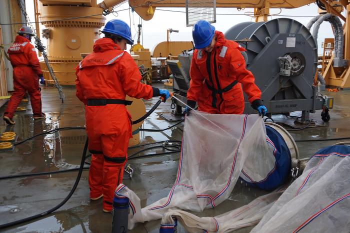 Janet Duffy-Anderson and Chrissy Hayes spraying nets to ensure they capture all the plankton from the tow in the caught end.