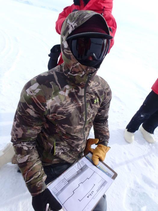 A person dressed in cold weather gear profiling a crack in the ice.