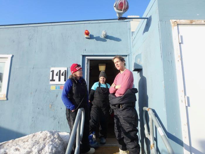 Three women getting ready in front of the dive hut.