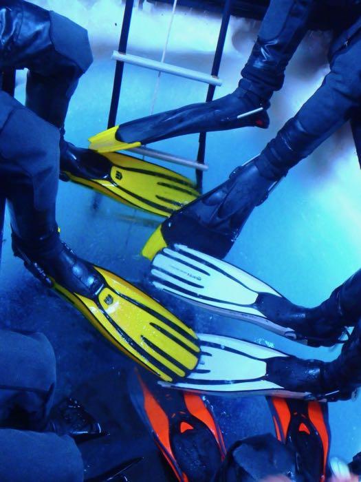 Diver's fins gathered around a hole in the sea ice.