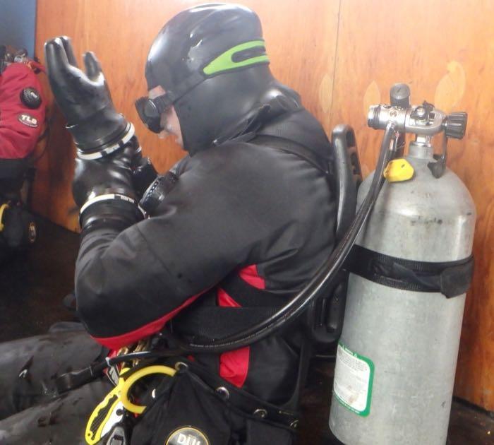 Aaron Toh putting on his dry suit gloves to go diving.