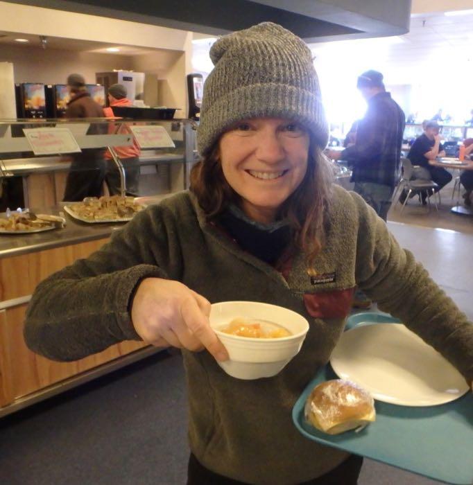 Amy Osborne with a bowl of oatmeal and a sandwich wrapped in plastic on a tray.