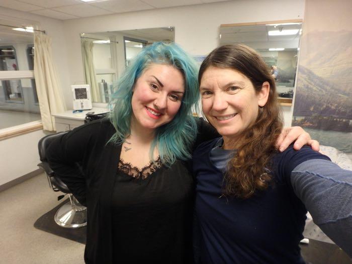 Two women standing in a barber shop.