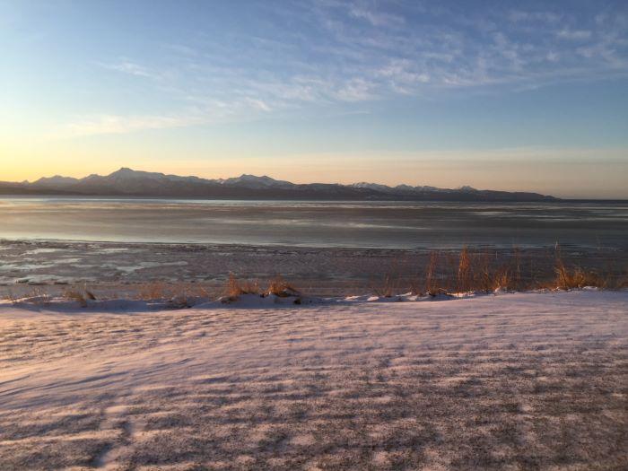 Snowy ground, beach, and thin sea ice at sunrise