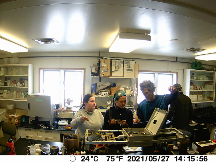 Liza, Sarah, and Steve stand behind the MISP in the lab. Jeremy stands in the background. 