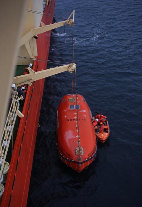 The crew practices dropping a lifeboat into the water