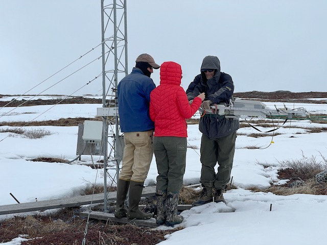 Jeremy, Sarah, and Steve stand in the snow while placing the MISP on the tram system. 