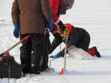 A science crew member uses an ice drill to bore a hole in the sea ice for an ice depth measurement. On the sea ice near the CCGS Louis S. St-Laurent in the Beaufort Sea. Photo by Dave Jones (PolarTREC 2017), Courtesy of ARCUS.