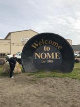 Piper Bartlett-Browne beside the Nome city sign.