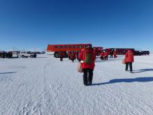 Walking across the icy air strip to the red shuttle Ivan the Terra Bus in Antarctica