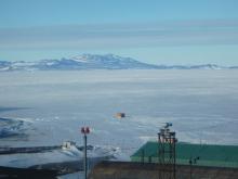 View of sea ice, mountains, and orange dive huts.