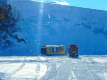 Pisten Bully arriving at a yellow and blue diving hut on the sea ice