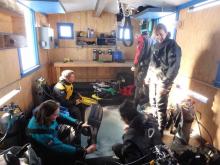 Divers gathered around a hole in the ice preparing to dive to the sea below.