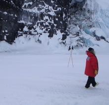 Karla Hiedelberg walking on the sea ice past the spot where the rock meets the ice