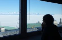 Amy looking out the window of the Crary Lab library at sea ice and mountains in the distance.