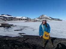 Amy Osborne with hut bag standing near Scott's Discovery Hut-a wooden structure