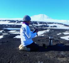 A person preparing tea in front of Mt. Erebus