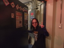 A woman giving the peace sign in front of an open door to a room with LiDAR technology inside.