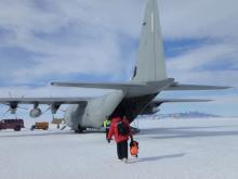 A person walks across the white ice to an airplane.