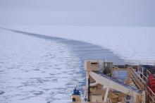 A boat moves through pack ice on the ocean.