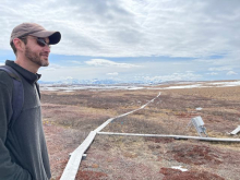 Jeremy stands in front of a field that has boardwalks. 