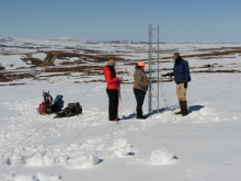 Sarah, Liza, and Jeremy stand in a snowy landscape around a wire tower. 