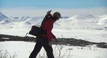 Sarah walks down the hill in front of beautiful Mountains at Imnavait carrying the Battery. 