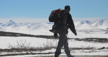 Steve walks down the hill at Imnavait in front of mountains with the jackhammer. 