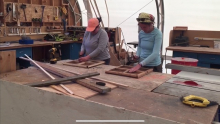 Liza and Sarah stand in a wood shop with hammers.