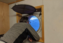 Dr. Ali Graham looks out a porthole on the R/V Nathaniel B. Palmer