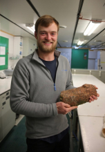 James Marschalek poses with a rock sample he collected from Sif Island