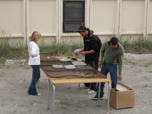 Aggu and Kunuk (Grl) build a makeshift grill as Sydney (US) looks on