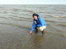 PolarTREC teacher Susan Steiner dipping a hand into the Arctic Ocean