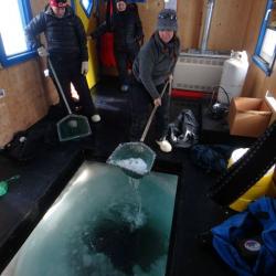 Scooping ice out of a dive hole in a dive hut